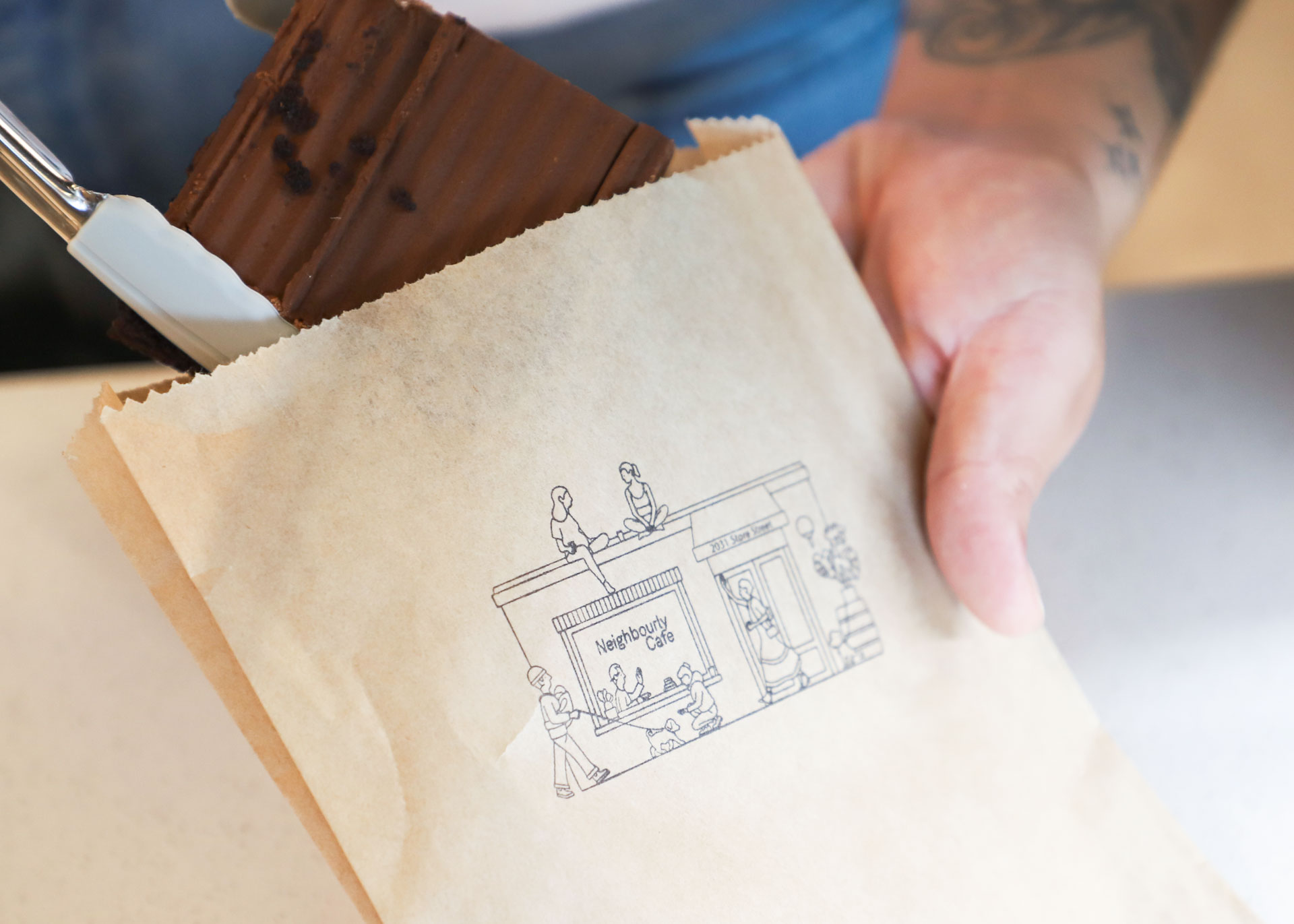 barista putting brownie into stamped paper bag